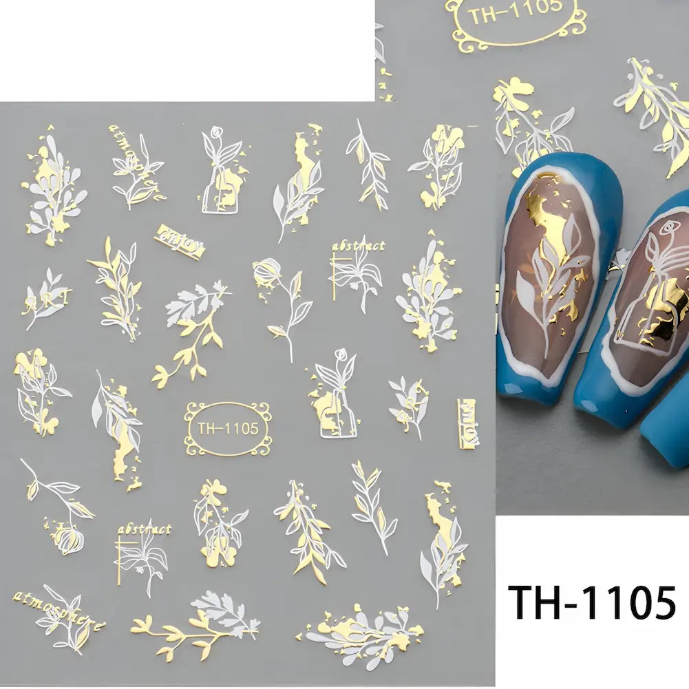 Adesivos para unhas com desenhos de folhas e flores em branco e dourado, aplicados em unhas com esmalte azul. Código: TH-1105.