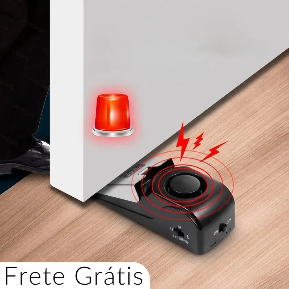 A imagem mostra um alarme de porta portátil sem fio anti-roubo em ação. O dispositivo está posicionado sob uma porta, com uma luz vermelha de alerta ao lado e ícones de ondas sonoras indicando que o alarme está disparando. Há uma pessoa tentando abrir a porta, destacando a eficácia do alarme em bloquear a entrada. Na parte inferior da imagem, está escrito "Frete Grátis". O design é compacto, com um interruptor de sensibilidade (H, M, L) e um botão de liga/desliga visíveis.