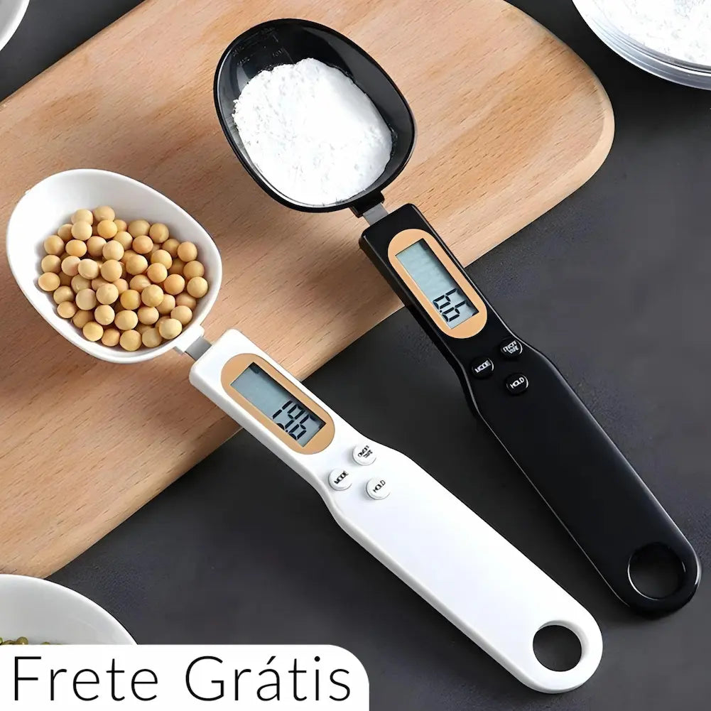 A imagem mostra duas balanças digitais de precisão em formato de colher, uma branca e outra preta, sobre uma superfície de madeira. A balança branca contém grãos, enquanto a balança preta contém pó branco. Ambas têm um display digital que mostra o peso dos ingredientes. Na parte inferior esquerda da imagem, está o texto "Frete Grátis", sugerindo uma oferta promocional. A imagem enfatiza a praticidade e a precisão das balanças para medir diferentes tipos de ingredientes na cozinha.