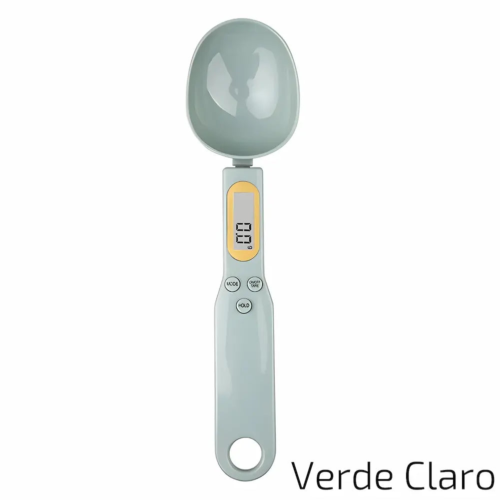 Uma balança digital de precisão em formato de colher, na cor verde claro. Apresenta um visor digital com detalhes em amarelo e três botões (MODE, TARE, HOLD) para facilitar o uso. A colher é espaçosa, adequada para medir ingredientes com precisão.