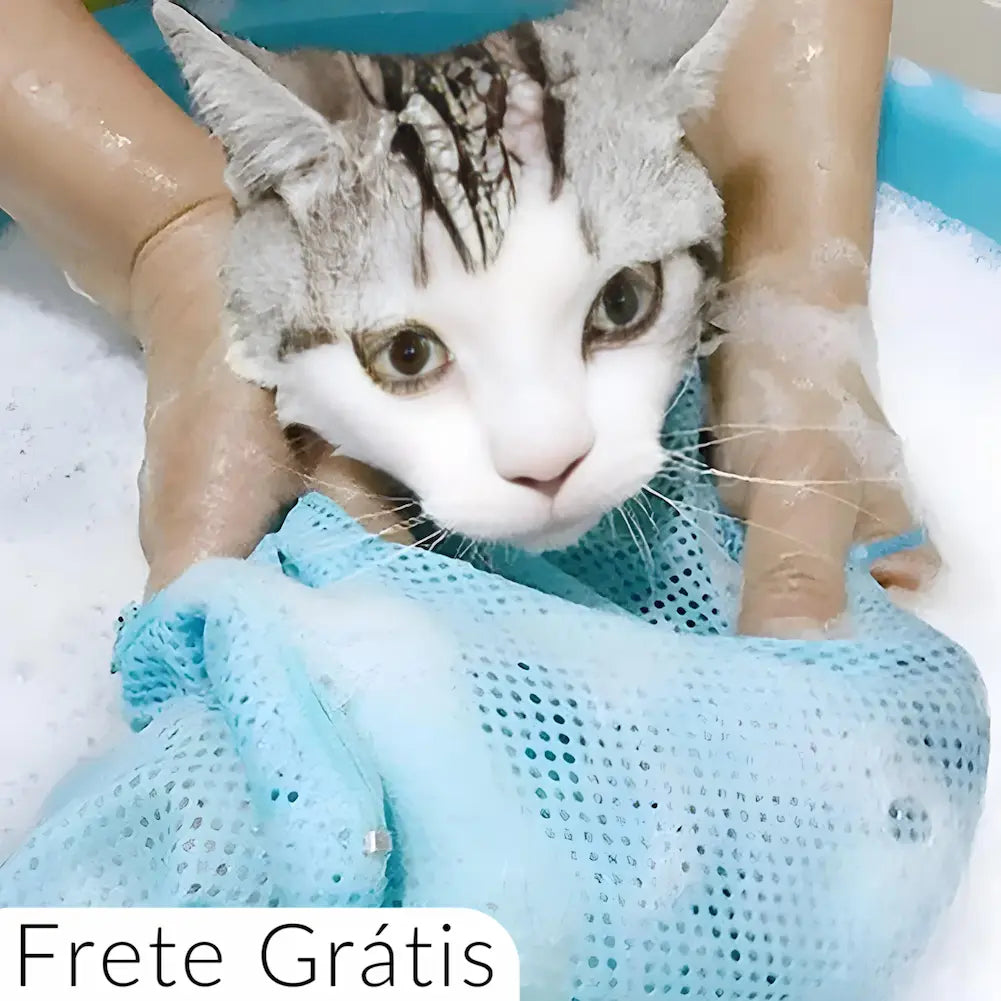  A imagem mostra um gato branco e cinza tomando banho, envolto em uma bolsa de rede azul clara. As mãos de uma pessoa estão segurando o gato dentro da bolsa, com água e espuma ao redor. O texto "Frete Grátis" está na parte inferior da imagem, em um fundo branco.