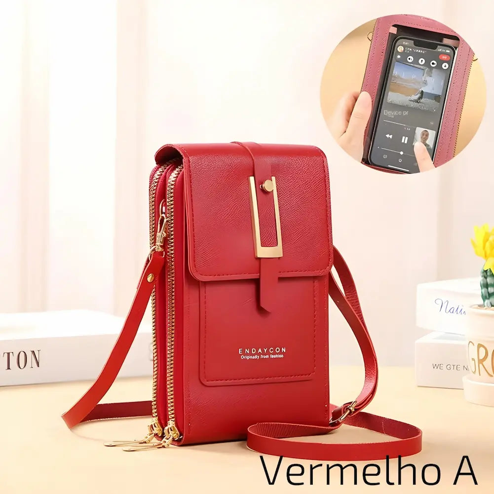 Uma bolsa de couro vermelho, com alça ajustável e fecho metálico dourado. Possui dois zíperes laterais e um bolso frontal com o nome da marca "ENDAYCON". No canto inferior direito, o código "Vermelho A", uma das opções de compra.