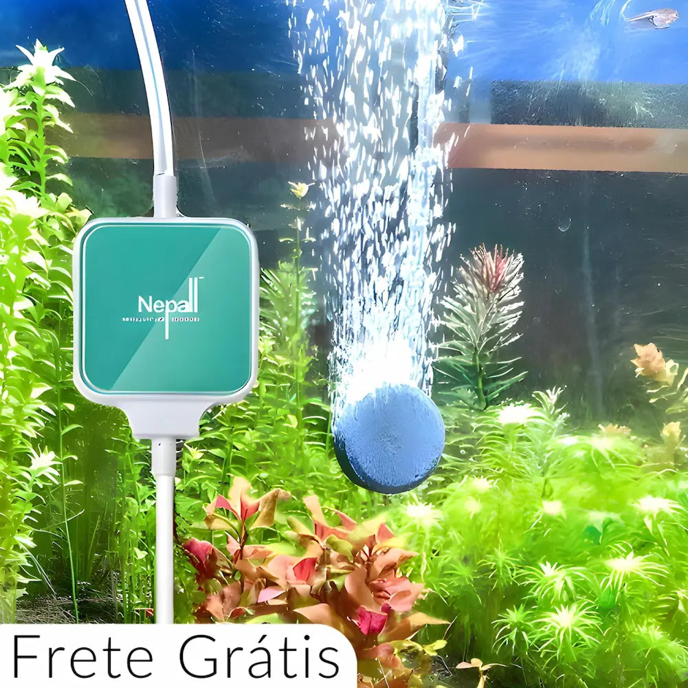 A imagem mostra um dispositivo verde e branco da marca "Nerall" conectado a um aquário. Uma pedra difusora libera bolhas de ar na água, com plantas aquáticas verdes e vermelhas ao fundo. O texto "Frete Grátis" está no canto inferior esquerdo. A cena destaca a funcionalidade do aerador em um ambiente aquático vibrante e bem cuidado.