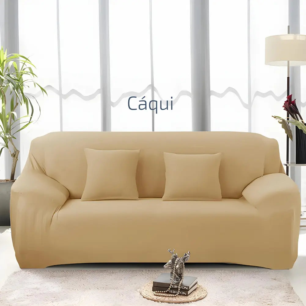 Imagem de uma sala clara com um sofá cor cáqui. O sofá tem três almofadas cáqui combinando. Ao lado esquerdo, há uma planta, e à direita, uma luminária de chão. Texto central: "Cáqui". Uma pequena mesa de centro com livros e uma escultura está à frente do sofá.