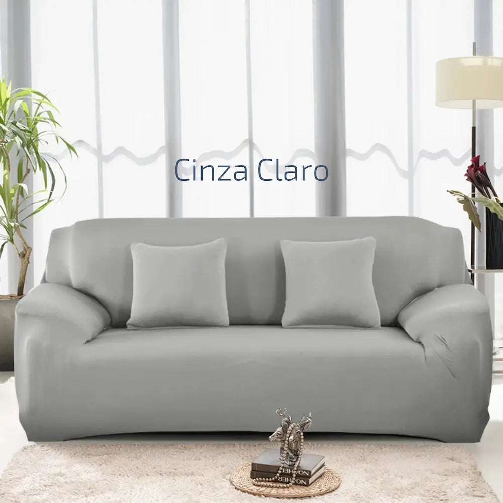  Imagem de uma sala clara com um sofá cinza claro. O sofá tem três almofadas cinza combinando. Ao lado esquerdo, há uma planta, e à direita, uma luminária de chão. Texto central: "Cinza Claro". Uma pequena mesa de centro com livros e uma escultura está à frente do sofá.