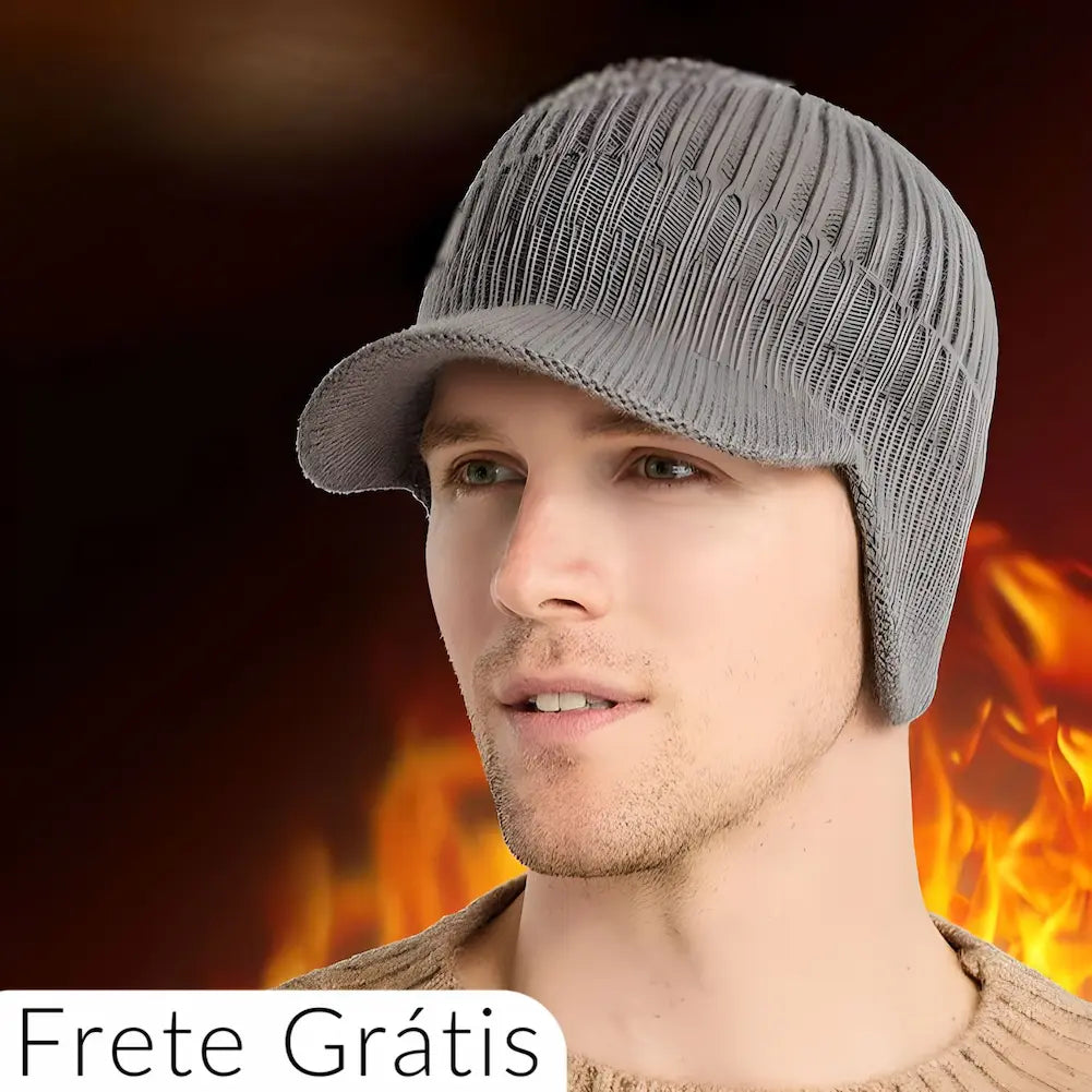 A imagem mostra um homem usando um chapéu de inverno cinza, feito de material tricotado, com aba frontal e proteção para as orelhas. O fundo possui uma chama, sugerindo calor e proteção contra o frio. Na parte inferior esquerda da imagem, há um texto em branco que diz "Frete Grátis". O homem veste uma blusa de lã bege.
