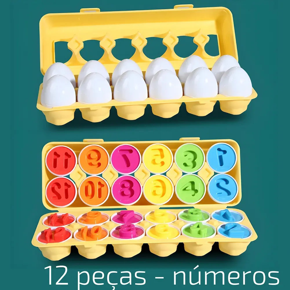 A imagem mostra uma bandeja amarela de ovos de plástico educativos em duas partes. Na parte superior, a bandeja está fechada, mostrando os ovos brancos inteiros. Na parte inferior, a bandeja está aberta, revelando os ovos divididos em metades com números coloridos em seu interior, de 1 a 12. As cores incluem vermelho, laranja, rosa, amarelo, verde e azul. Na parte inferior da imagem, está escrito "12 peças - números" em texto branco. O fundo é verde.