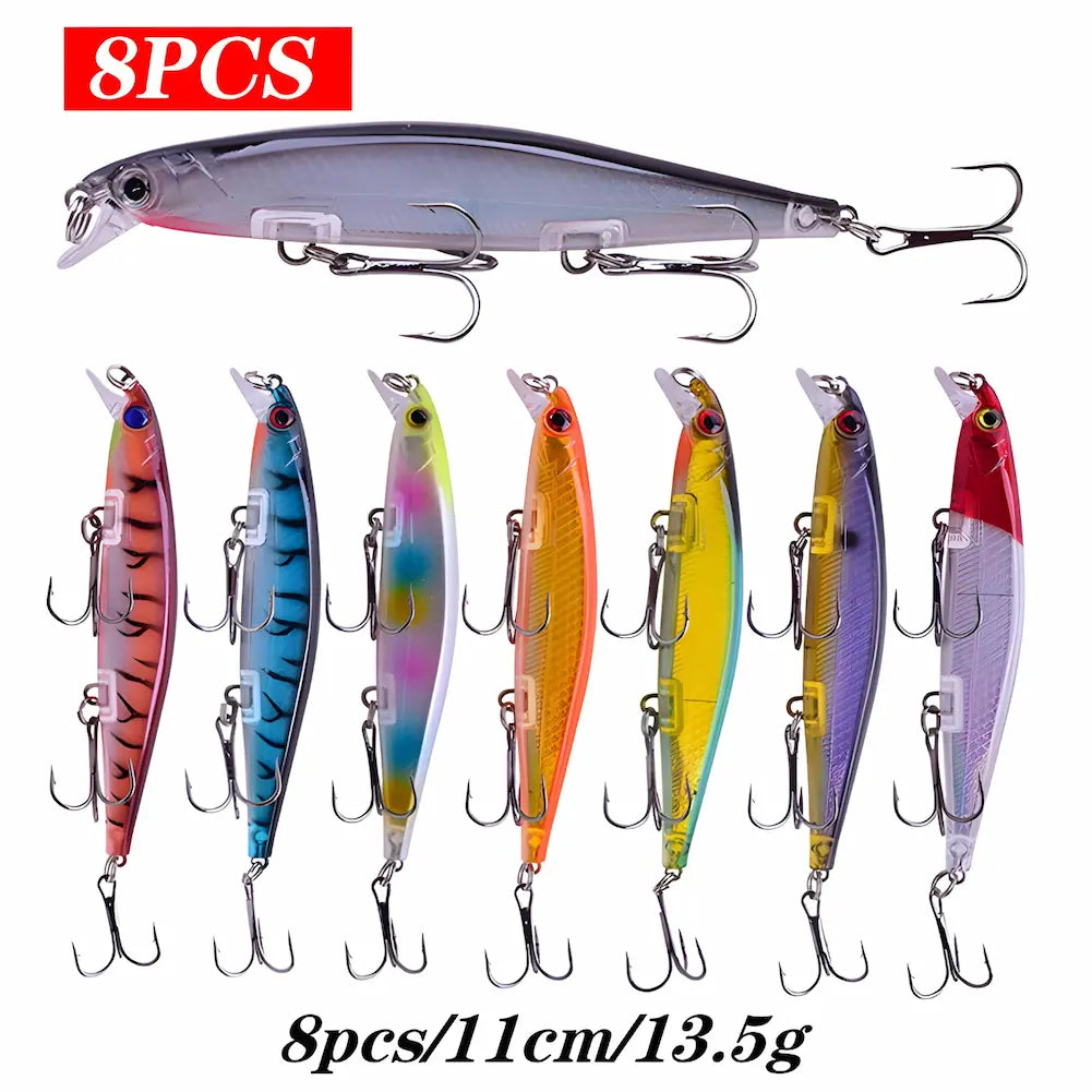 A imagem mostra um conjunto de oito iscas de pesca artificiais, cada uma com um design e cores diferentes. As iscas têm 11 cm de comprimento e pesam 13.5g. As cores variam entre rosa, azul, multicolorida, laranja, amarela, roxa e vermelha com branco. Cada isca possui três anzóis triplos e a imagem destaca a variedade de cores e designs. Acima, há um texto "8PCS" em vermelho.