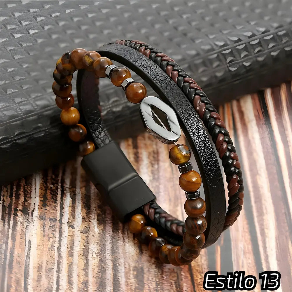 Pulseira composta por couro preto e marrom trançado, adornada com contas de pedras naturais em tons marrons. Destaca-se um detalhe metálico em forma de losango. Fecho preto. Estilo: 13.