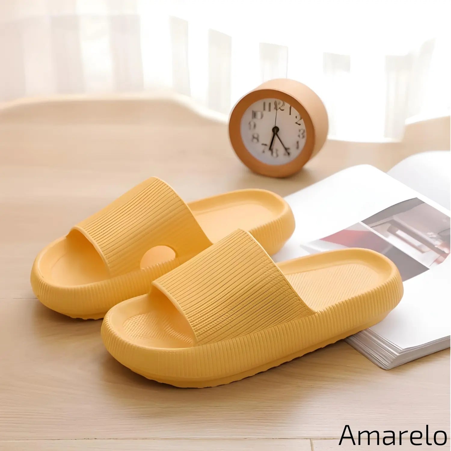Imagem mostrando um par de chinelos amarelos. Eles estão dispostos sobre uma superfície de madeira clara, ao lado de um relógio de mesa laranja e uma revista aberta, em um ambiente iluminado por luz natural.