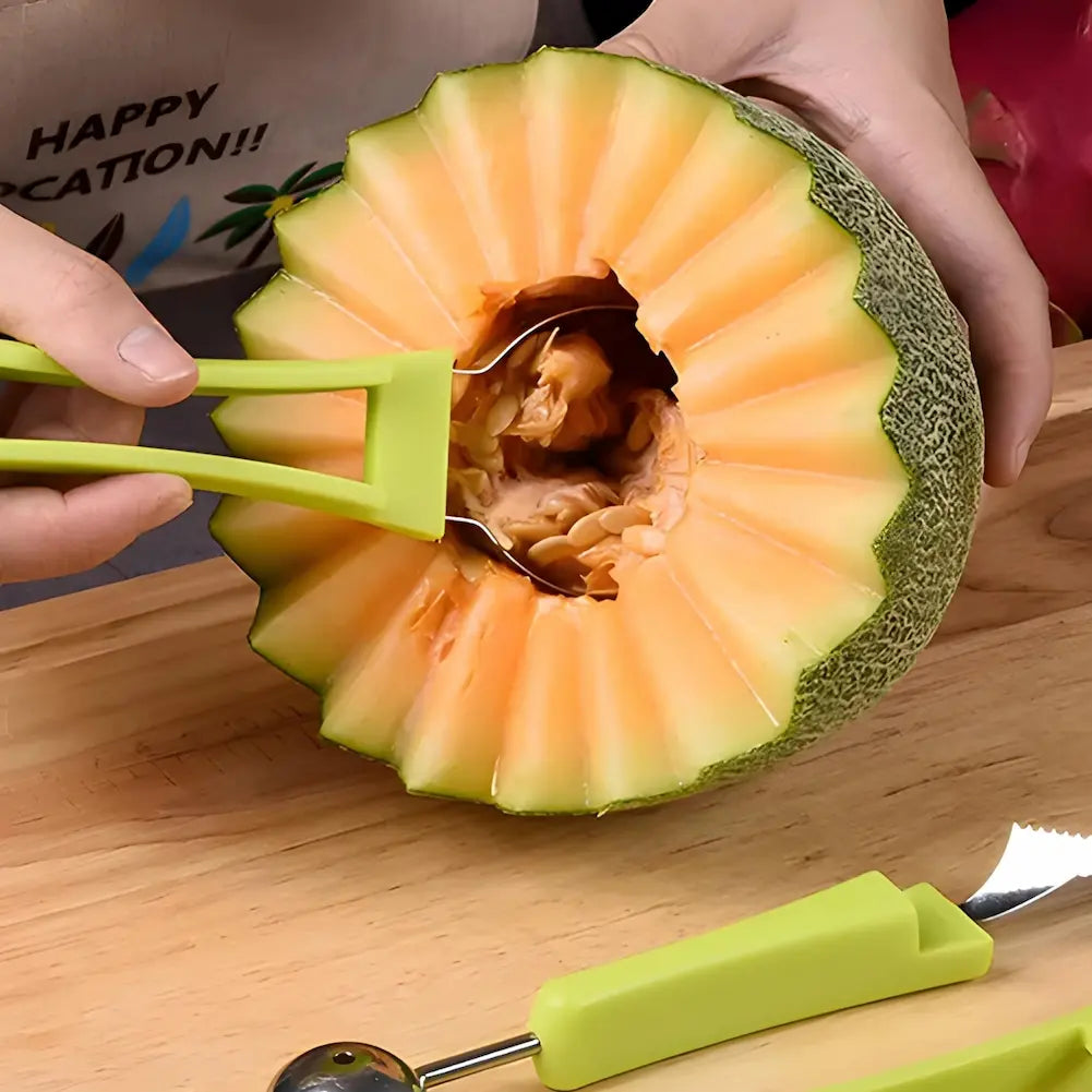  A imagem mostra um melão cortado em forma decorativa com uma borda em zigue-zague. Uma mão está usando uma ferramenta verde para retirar as sementes do melão. A ferramenta tem uma ponta larga e plana. No fundo, há mais utensílios de cozinha verdes e uma faca com lâmina serrilhada sobre uma tábua de madeira.