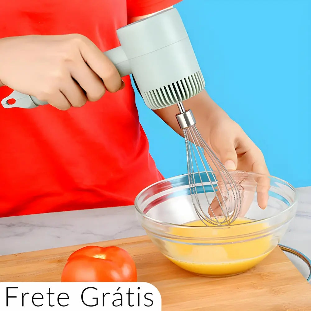  A imagem mostra uma pessoa usando um batedor de mão elétrico verde claro para misturar uma substância amarela em uma tigela de vidro. A pessoa veste uma camisa vermelha e está em uma bancada de cozinha com uma tábua de madeira e um tomate ao lado. No canto inferior esquerdo, há um texto "Frete Grátis".