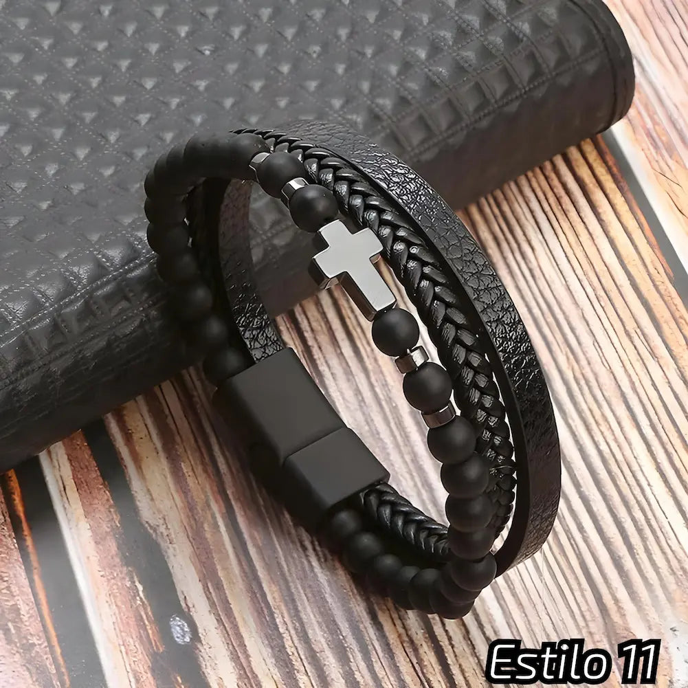 Pulseira preta com tiras de couro trançado e texturizado, adornada com contas escuras e um pequeno crucifixo metálico. Fecho preto discreto, perfeito para um visual moderno e elegante. Estilo: 11.