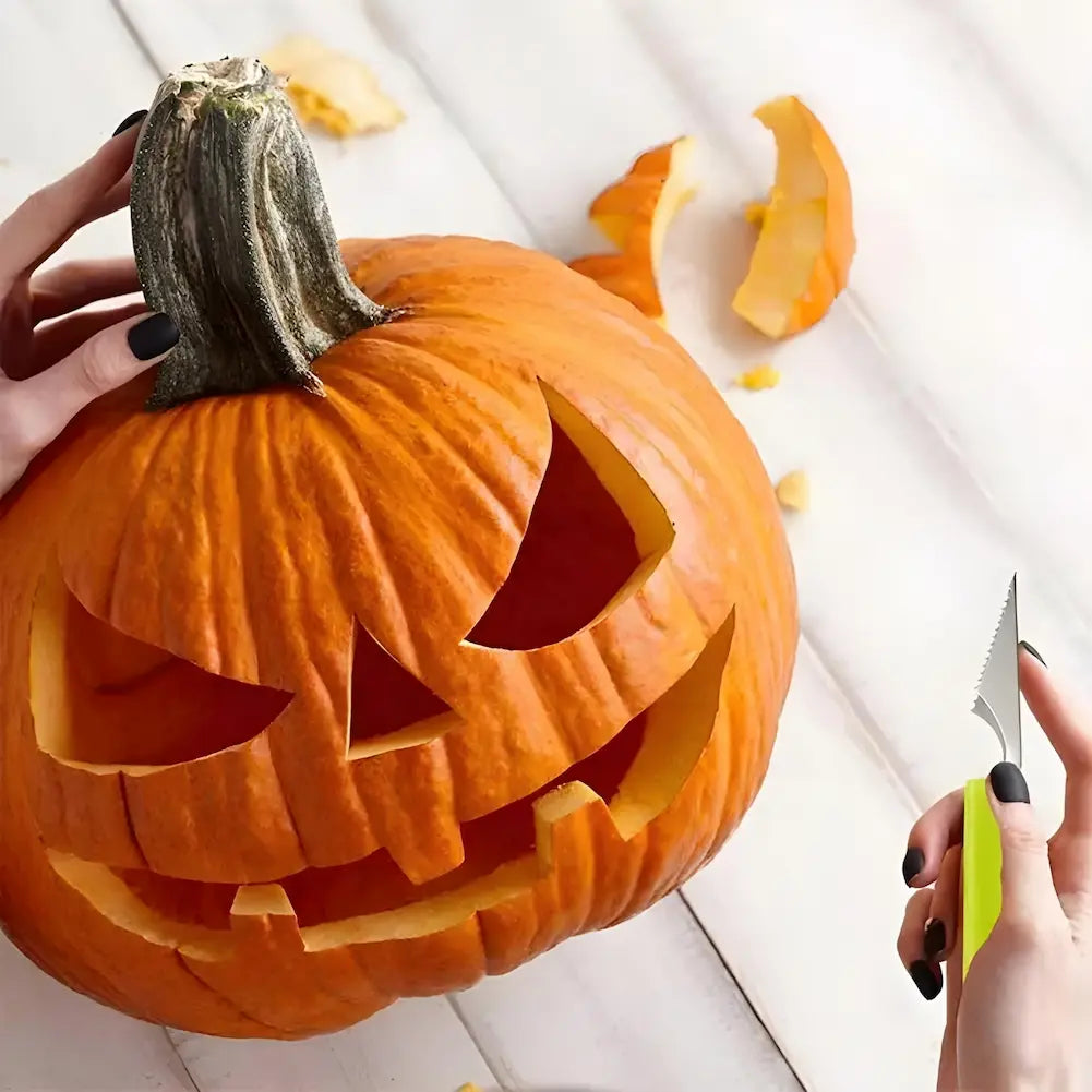  A imagem mostra uma abóbora laranja esculpida com uma face de Halloween, com olhos triangulares e boca sorridente. Uma mão segura a abóbora pelo caule, enquanto outra mão usa uma faca serrilhada com cabo verde para fazer os cortes. Pedaços de abóbora cortados estão espalhados ao redor.