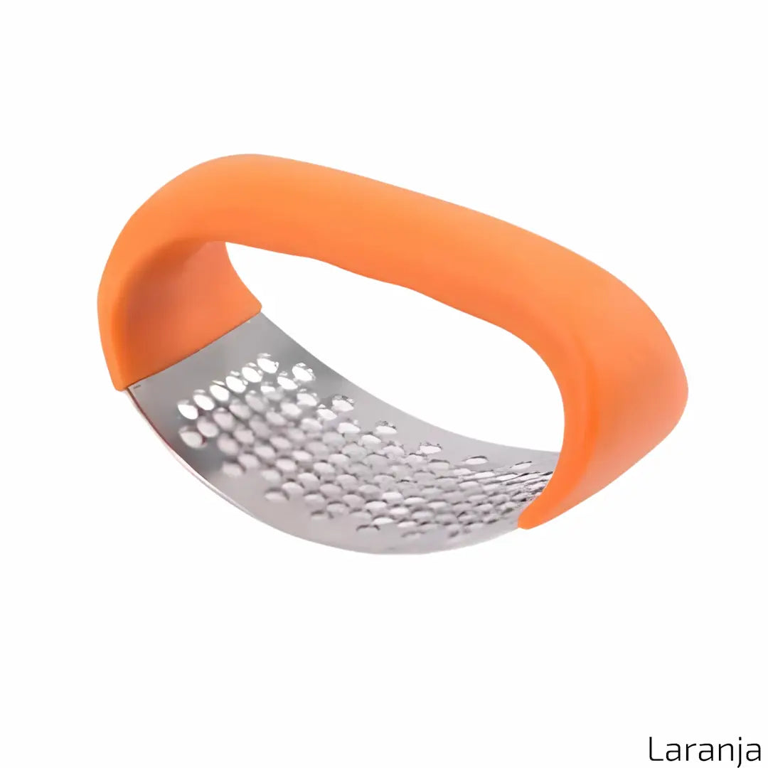A imagem exibe um amassador de alho com cabo curvado na cor laranja e uma superfície metálica perfurada para triturar alimentos. O design é ergonômico e prático, ideal para facilitar o preparo de temperos. No canto inferior direito, está o texto "Laranja".