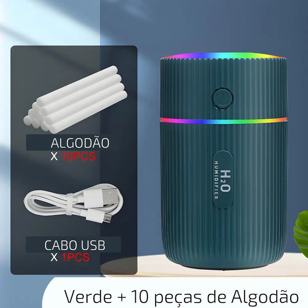 Imagem mostrando um umidificador de ar portátil verde escuro com textura ondulada, emitindo luzes coloridas no topo. Ao lado, há uma representação dos acessórios incluídos: dez peças de algodão cilíndricas e um cabo USB branco. Abaixo dos acessórios, há textos indicando "ALGODÃO X 10PCS" e "CABO USB X 1PCS". Na parte inferior da imagem, lê-se "Verde + 10 peças de Algodão".
