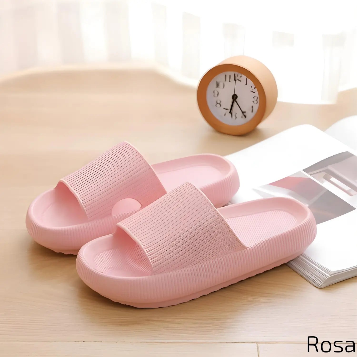 Imagem mostrando um par de chinelos rosas. Eles estão dispostos sobre uma superfície de madeira clara, ao lado de um relógio de mesa laranja e uma revista aberta, criando uma atmosfera acolhedora e suave.