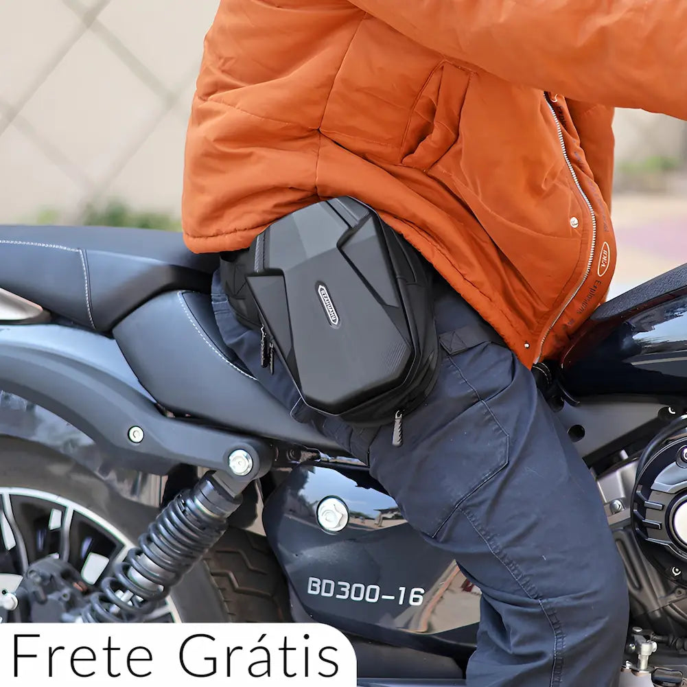 Imagem de uma pessoa sentada em uma motocicleta, usando uma jaqueta laranja e calças pretas. A pessoa está vestindo uma mochila preta Blazewind presa à cintura. A mochila tem design aerodinâmico e textura em fibra de carbono, com a marca "Blazewind" visível. Na parte inferior esquerda da imagem, há o texto "Frete Grátis". O fundo mostra detalhes da motocicleta e uma parede desfocada.