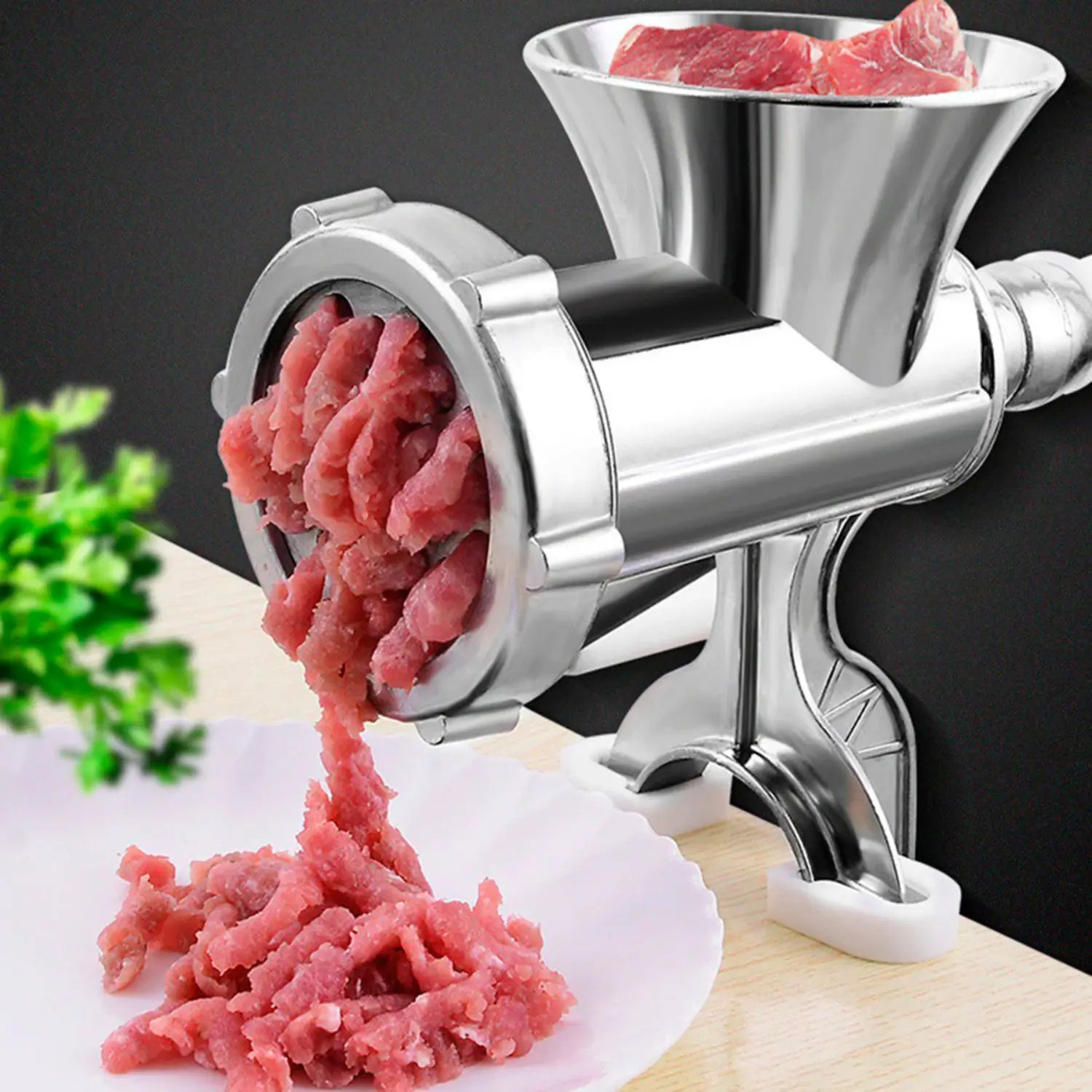 A imagem mostra um moedor de carne de metal em funcionamento, com carne sendo processada e saindo como carne moída. O moedor é robusto e eficiente, com o design metálico proporcionando durabilidade e facilidade no uso. Ao fundo, um pedaço de carne é visível, sugerindo o início do processo de moagem. O prato à frente já contém a carne moída, demonstrando a utilidade do produto para moer carne em casa.