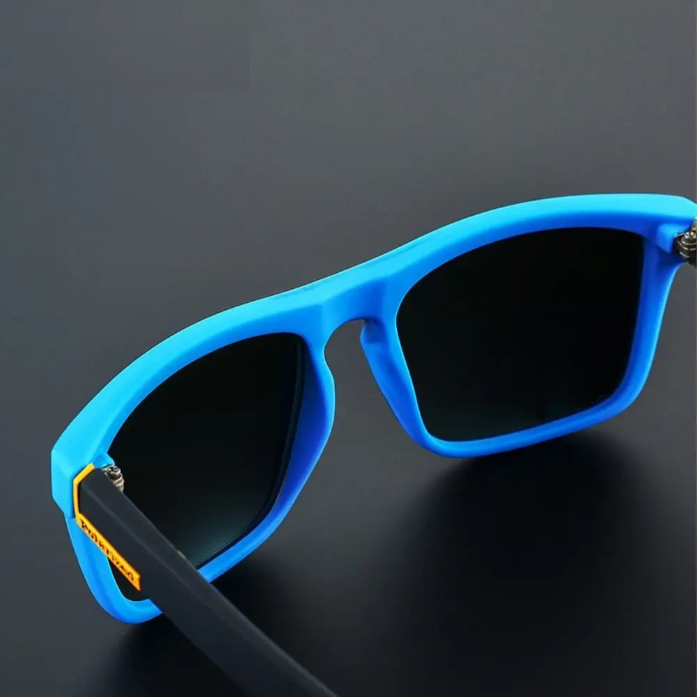 um óculos de sol com armação azul vibrante e lentes escuras. A haste é preta com uma pequena área amarela próximo à articulação com a armação.