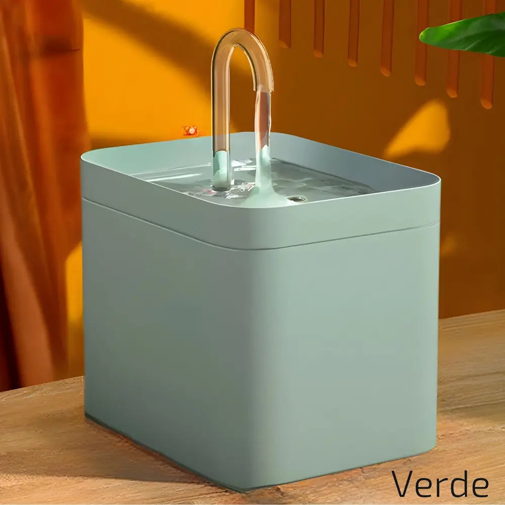 Imagem de um bebedouro quadrado verde para pets, com um tubo curvado de onde a água sai suavemente. O fundo em tons de laranja e verde complementa o design. Este é o modelo "Verde", uma escolha elegante para um ambiente colorido.