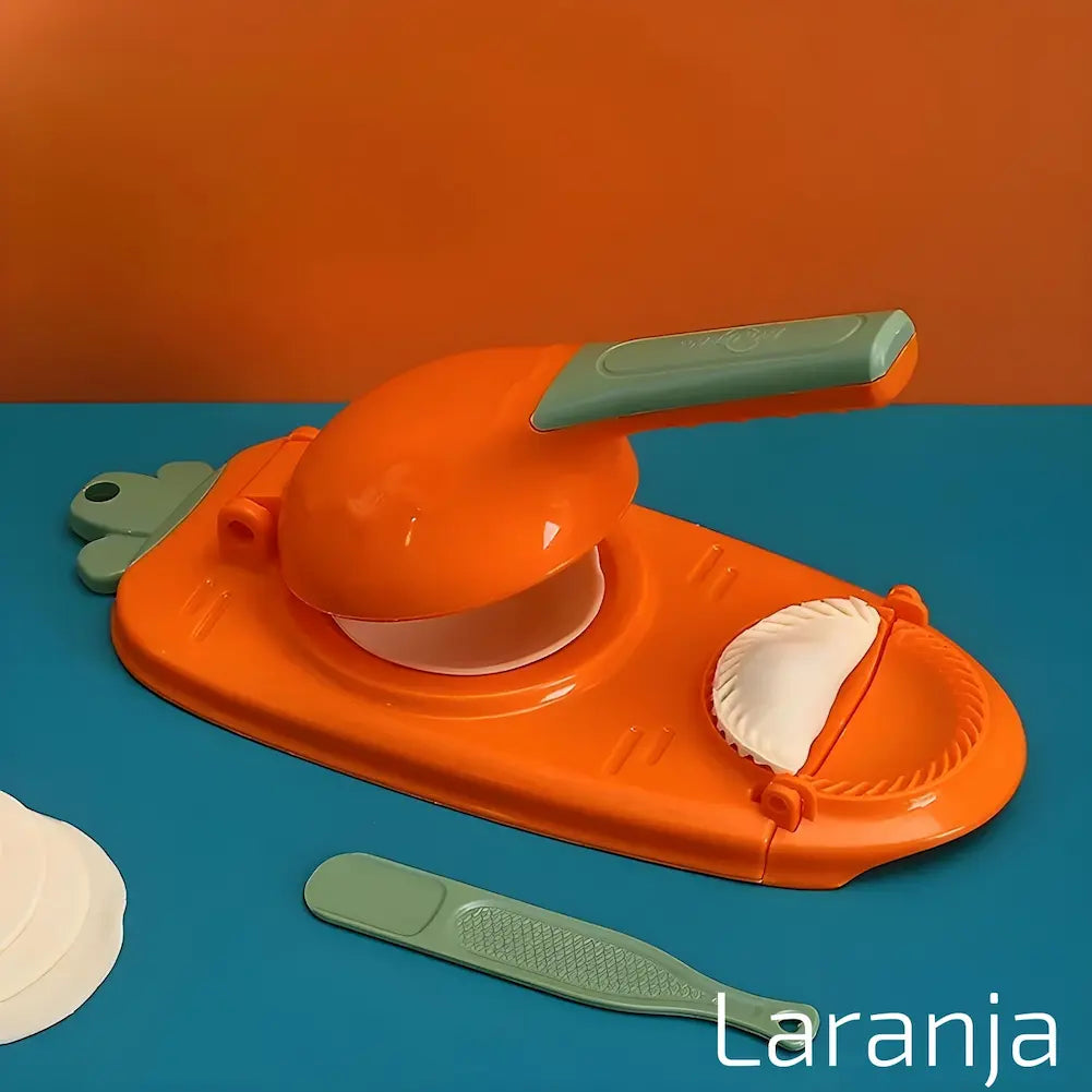  A imagem mostra um modelador manual de dumplings laranja sobre uma superfície azul e uma parede laranja. O aparelho está aberto com um disco de massa no centro e um dumpling moldado ao lado. Há uma espátula verde e um disco de massa adicional ao lado. O texto "Laranja" está na parte inferior direita.