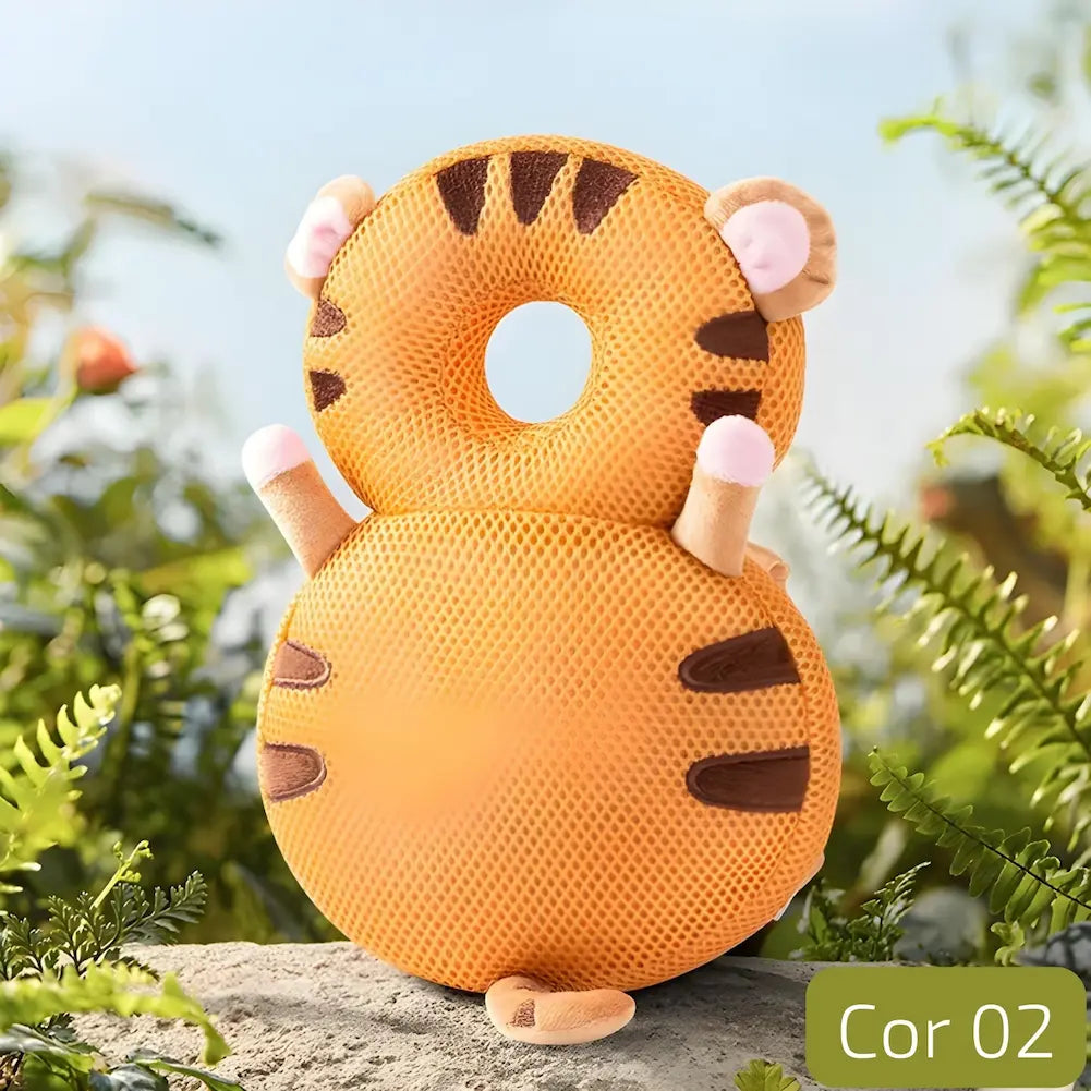  A imagem mostra uma almofada anti-queda para bebês em formato de tigre. A almofada é laranja com listras marrons e detalhes em rosa nas orelhas e patas. Possui um buraco central para proteger a cabeça do bebê. Está posicionada em um ambiente ao ar livre com plantas verdes ao redor, proporcionando uma sensação de segurança e naturalidade. No canto inferior direito, há a indicação "Cor 02".