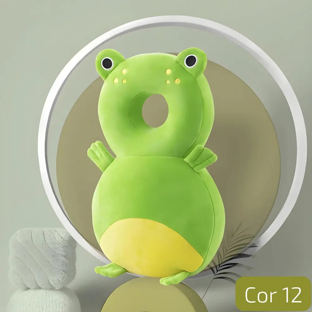  A imagem mostra uma almofada anti-queda para bebês em formato de sapo. A almofada é verde com detalhes em amarelo na barriga e nas patas. Possui um buraco central para proteger a cabeça do bebê. Está posicionada em um cenário com um fundo geométrico e cores suaves, criando uma atmosfera calma e agradável. No canto inferior direito, há a indicação "Cor 12".