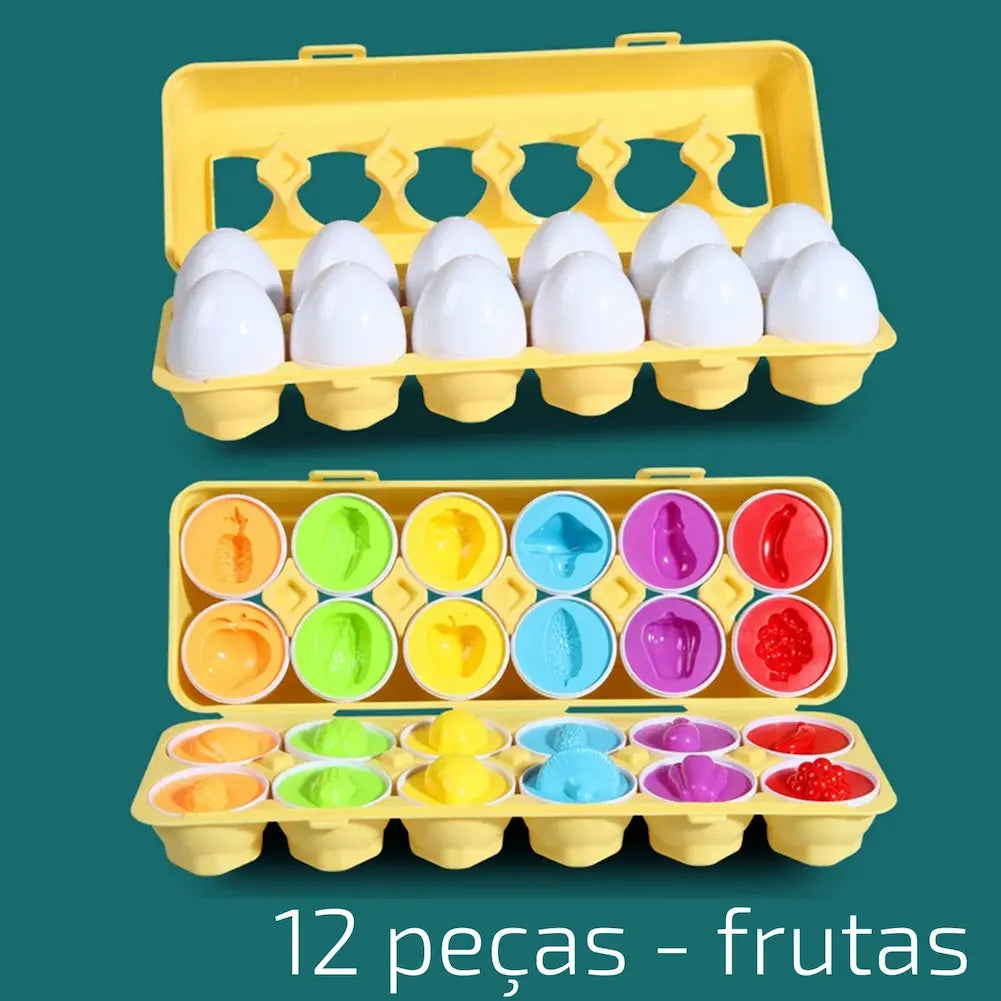 A imagem mostra uma bandeja amarela de ovos de plástico educativos. Na parte superior, a bandeja está fechada, mostrando ovos brancos inteiros. Na parte inferior, a bandeja está aberta, revelando ovos com metades coloridas exibindo formas de frutas, como abacaxi, maçã, banana e morango. O fundo é verde. Na parte inferior está escrito "12 peças - frutas".