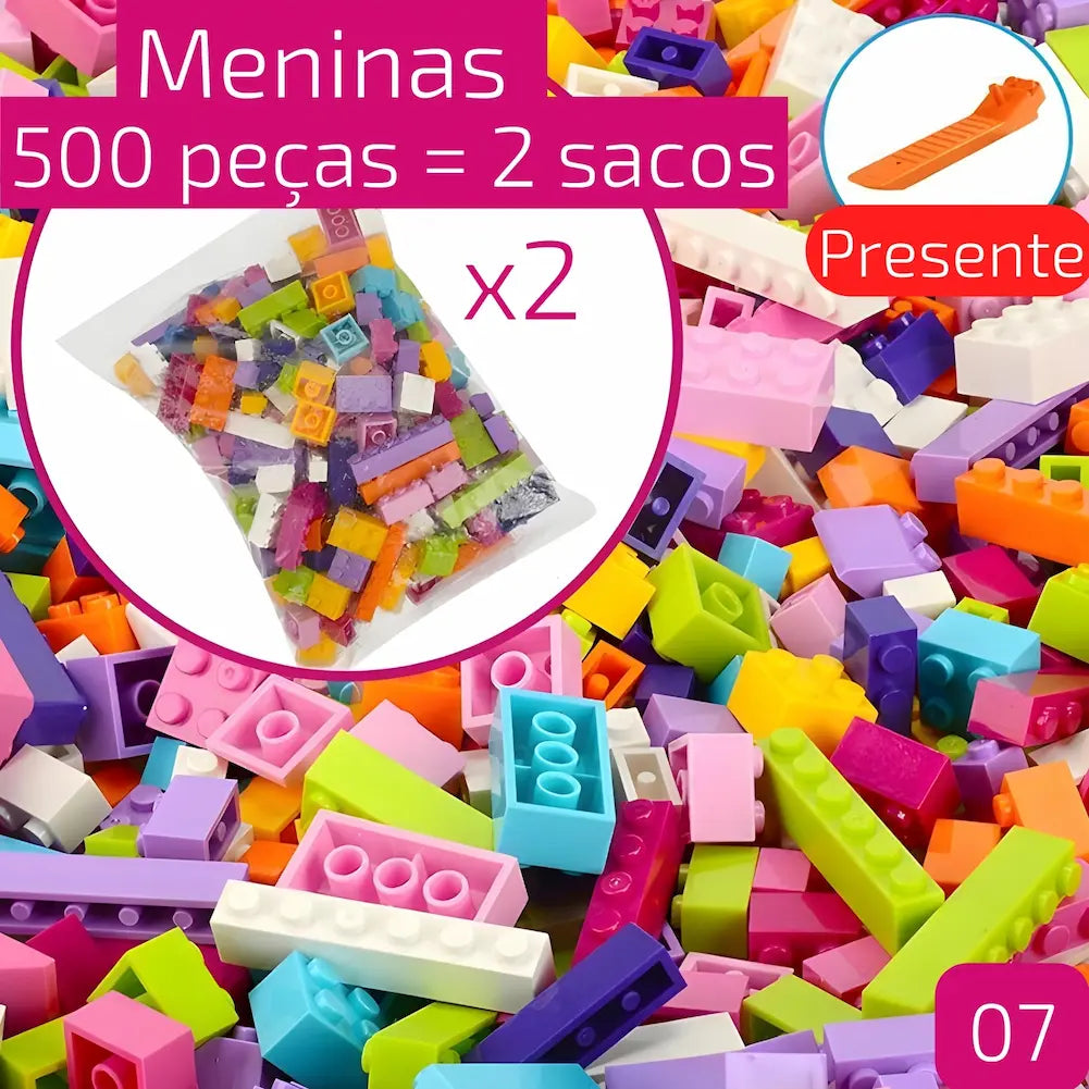 A imagem mostra dois sacos com 500 peças de blocos de construção coloridos para meninas, com a quantidade destacada em um círculo rosa no centro. Há uma ferramenta laranja de presente indicada no canto superior direito. Os blocos de construção estão espalhados no fundo da imagem.