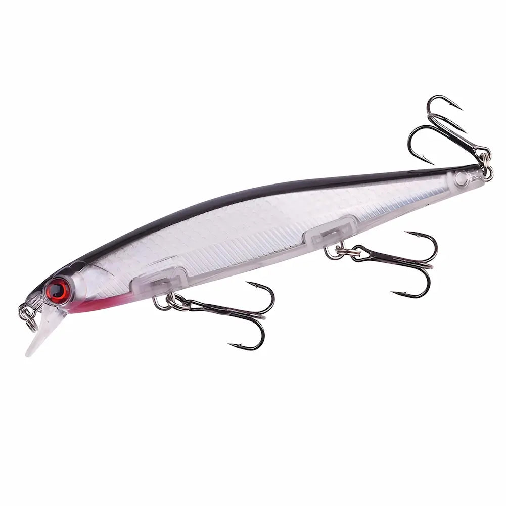 A imagem mostra uma isca de pesca artificial com formato alongado. A isca é predominantemente prateada com a parte superior preta e detalhes em vermelho próximo à cabeça. Possui olhos vermelhos e uma pequena pala transparente na frente. Há três anzóis triplos de cor escura presos ao corpo da isca. O fundo é branco, destacando os detalhes.