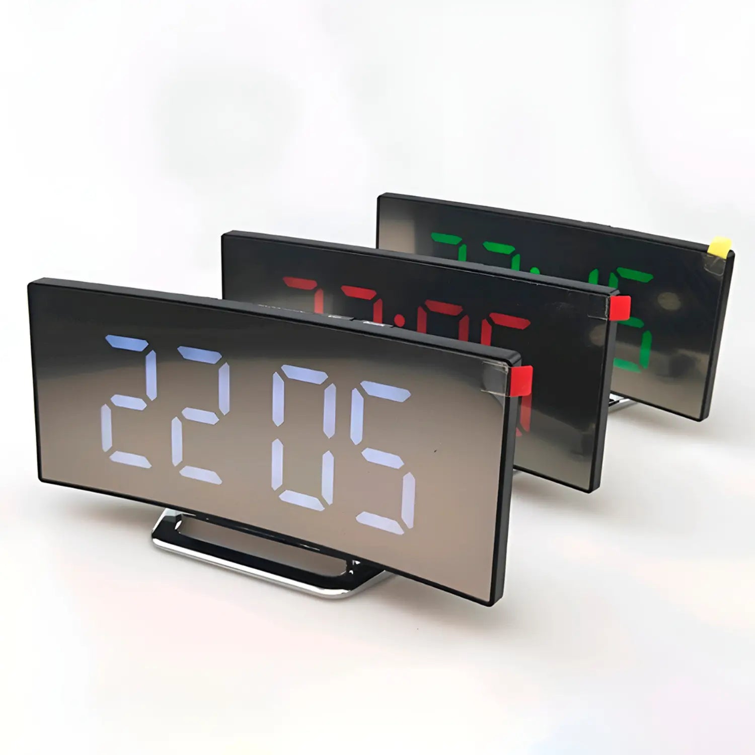 A imagem mostra três relógios digitais retangulares com números grandes, exibindo horários diferentes em displays coloridos. O primeiro relógio tem números azuis, o segundo verde e o terceiro vermelho, com pequenos detalhes coloridos nas laterais (amarelo e vermelho). Eles têm uma base metálica e estão posicionados sobre um fundo branco, com o texto "Frete Grátis" na parte inferior. O design é moderno e simples, destacando as cores e o formato do relógio.