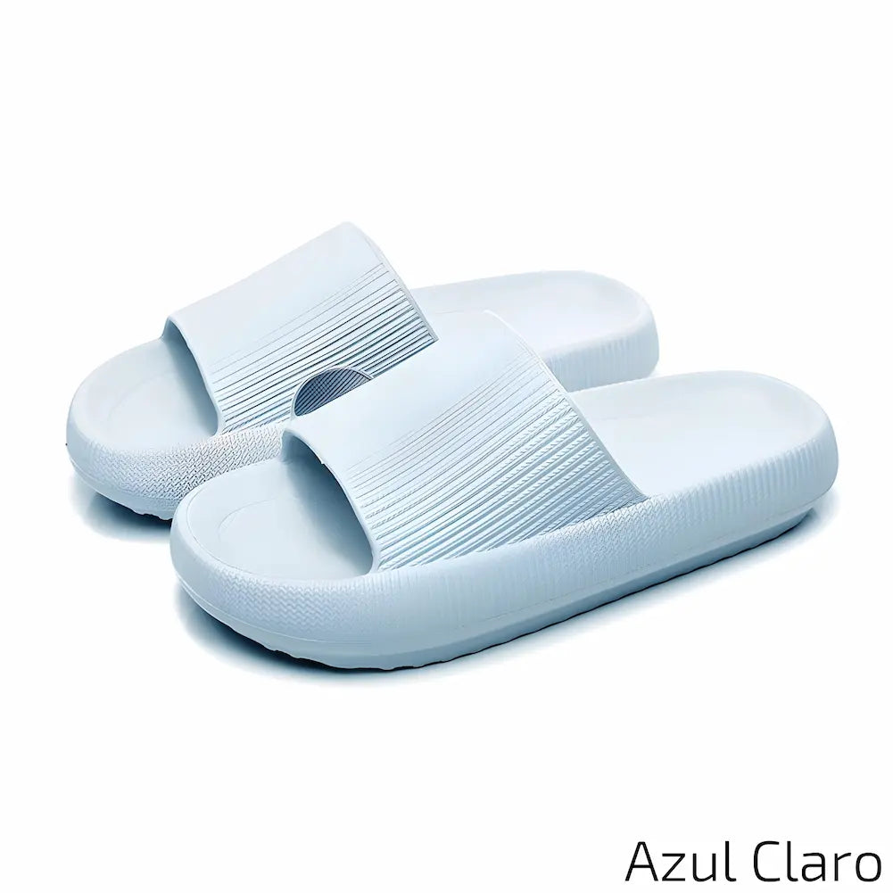 Imagem mostrando um par de chinelos azul claro. Eles estão dispostos sobre uma superfície branca, destacando a cor suave e o design antiderrapante dos chinelos.