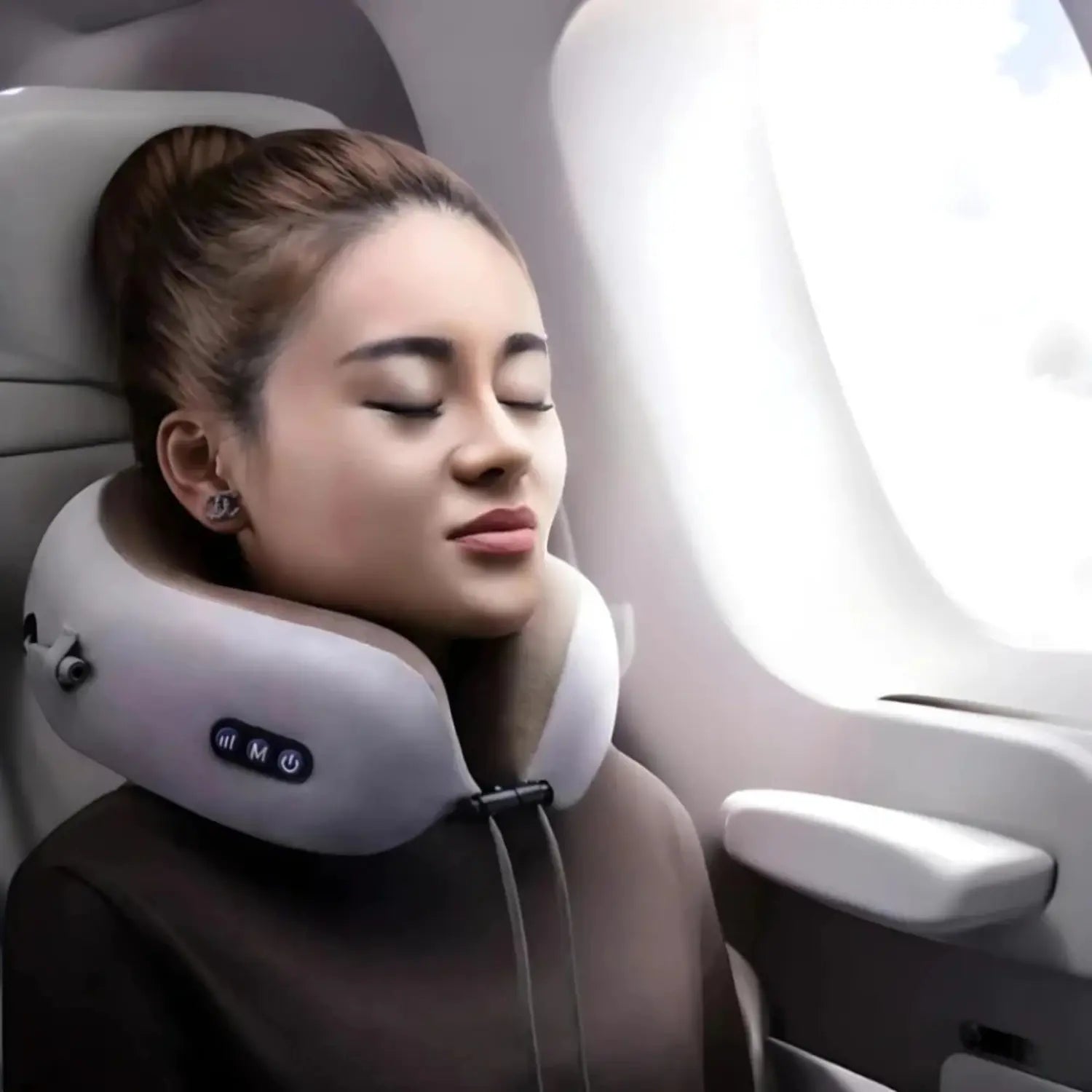A imagem mostra uma mulher relaxando em um avião enquanto usa um travesseiro de massagem para o pescoço. Ela está com os olhos fechados, aparentando conforto e alívio, enquanto o dispositivo proporciona suporte e massagem. O travesseiro tem botões de controle visíveis na lateral e oferece uma experiência relaxante durante a viagem.